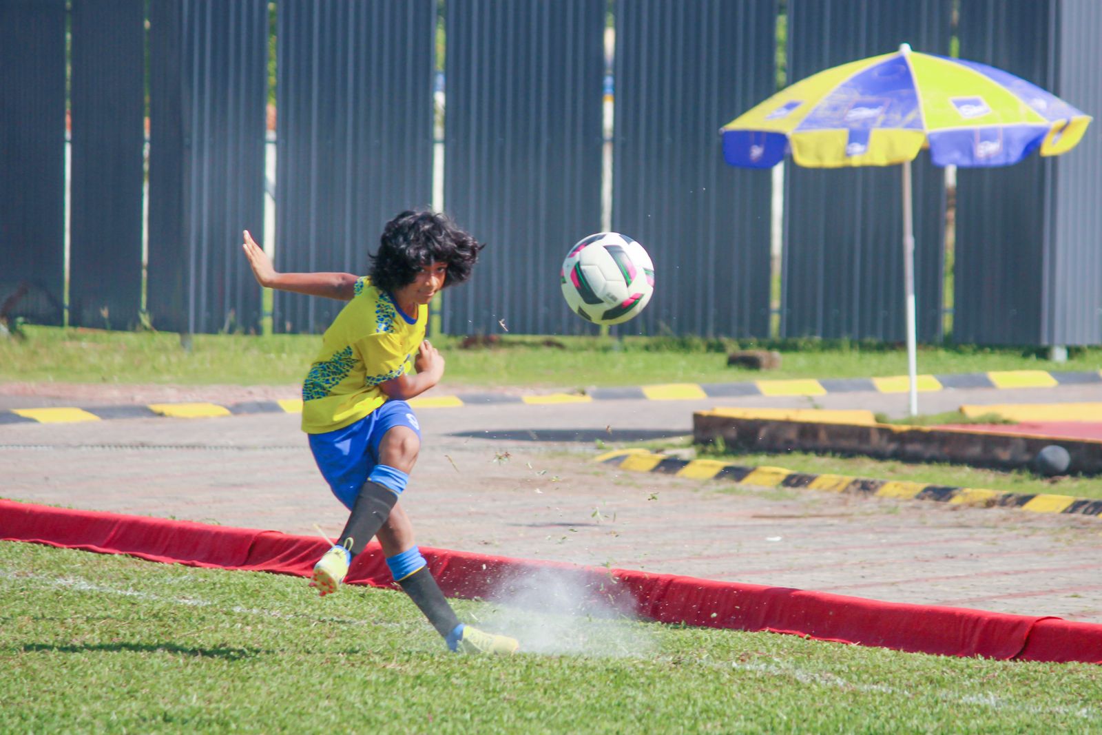 A child striking a football on a GEMS school field.