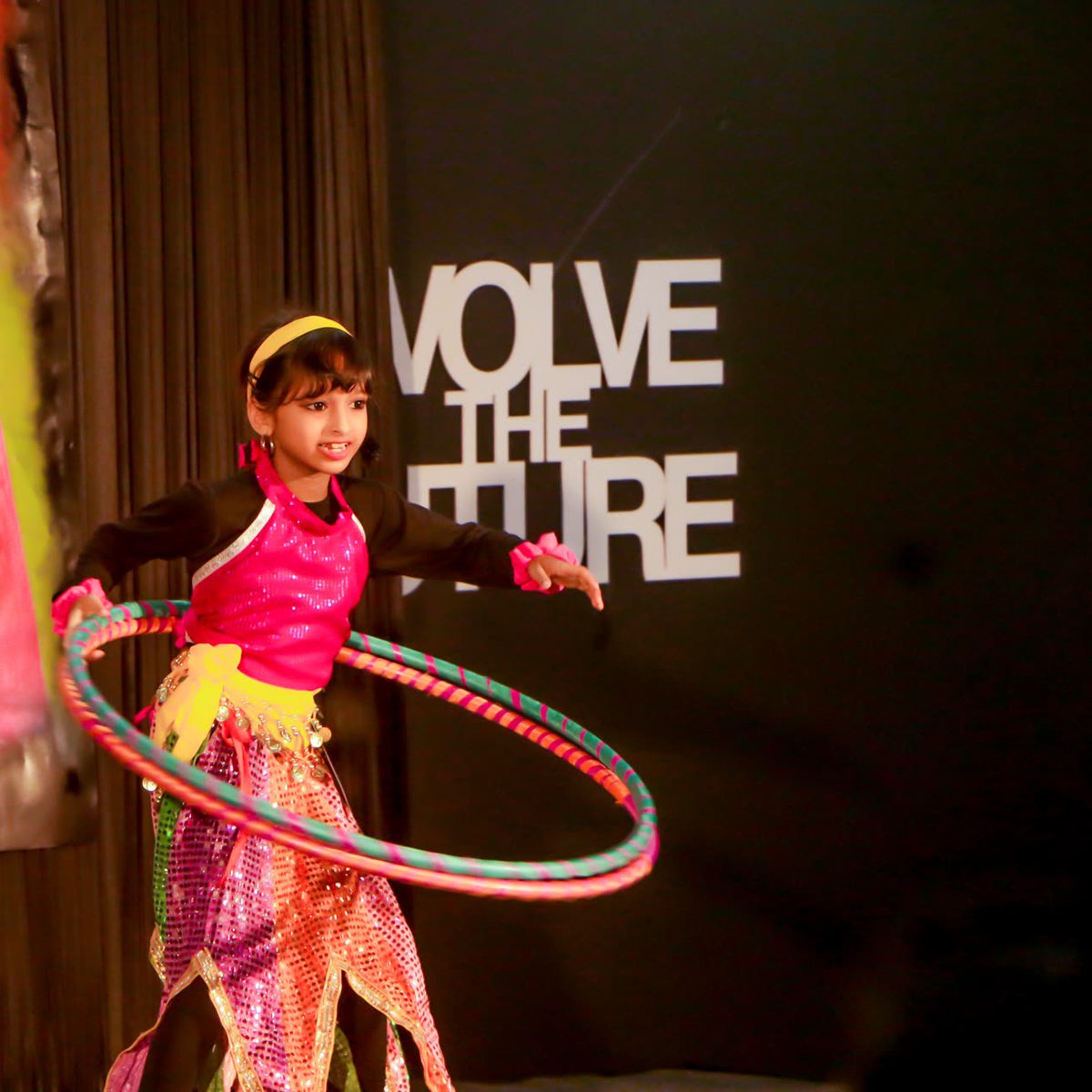 A child performing with a hoop on stage at a GEMS school.