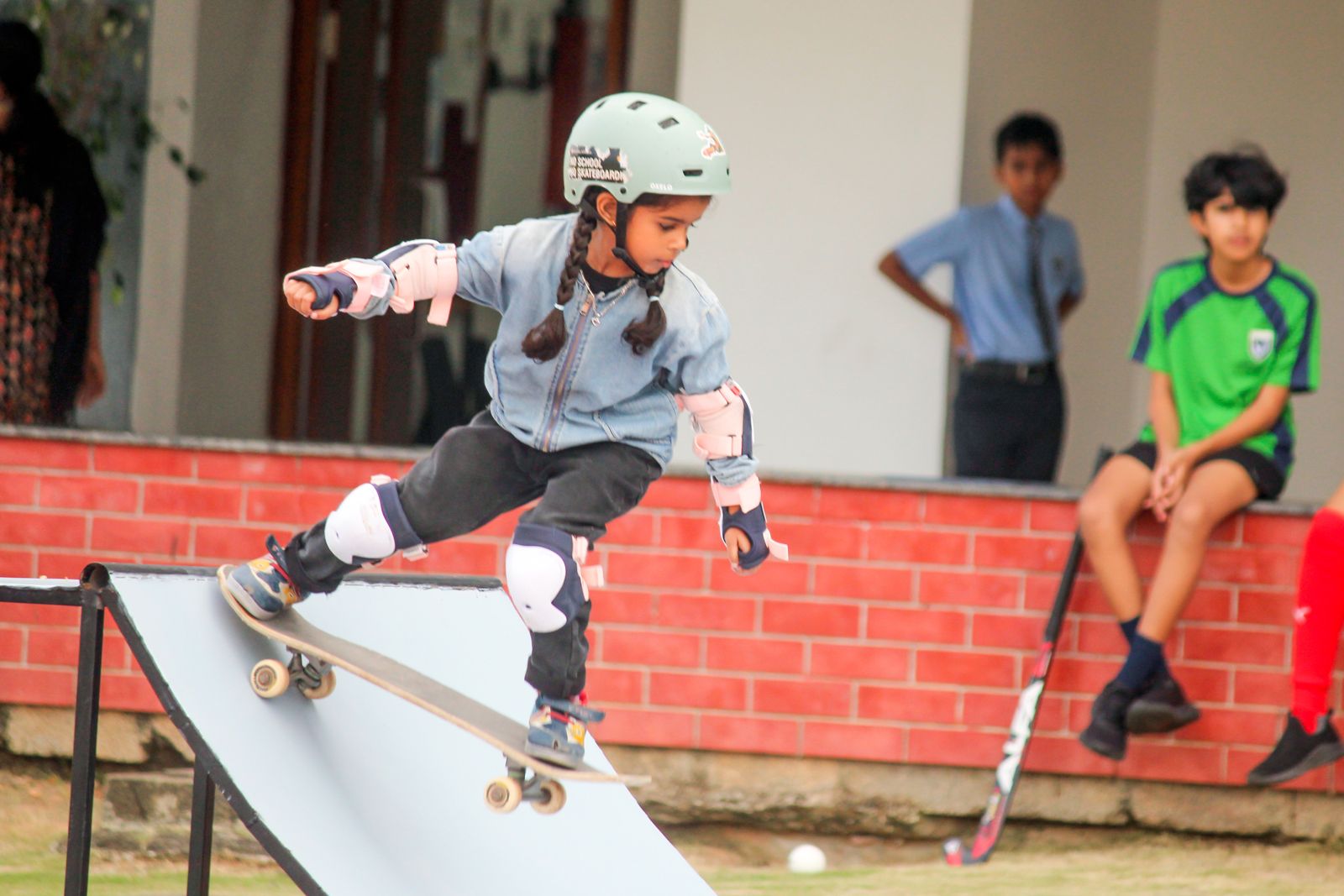 A child riding a skateboard ramp in full safety gear.