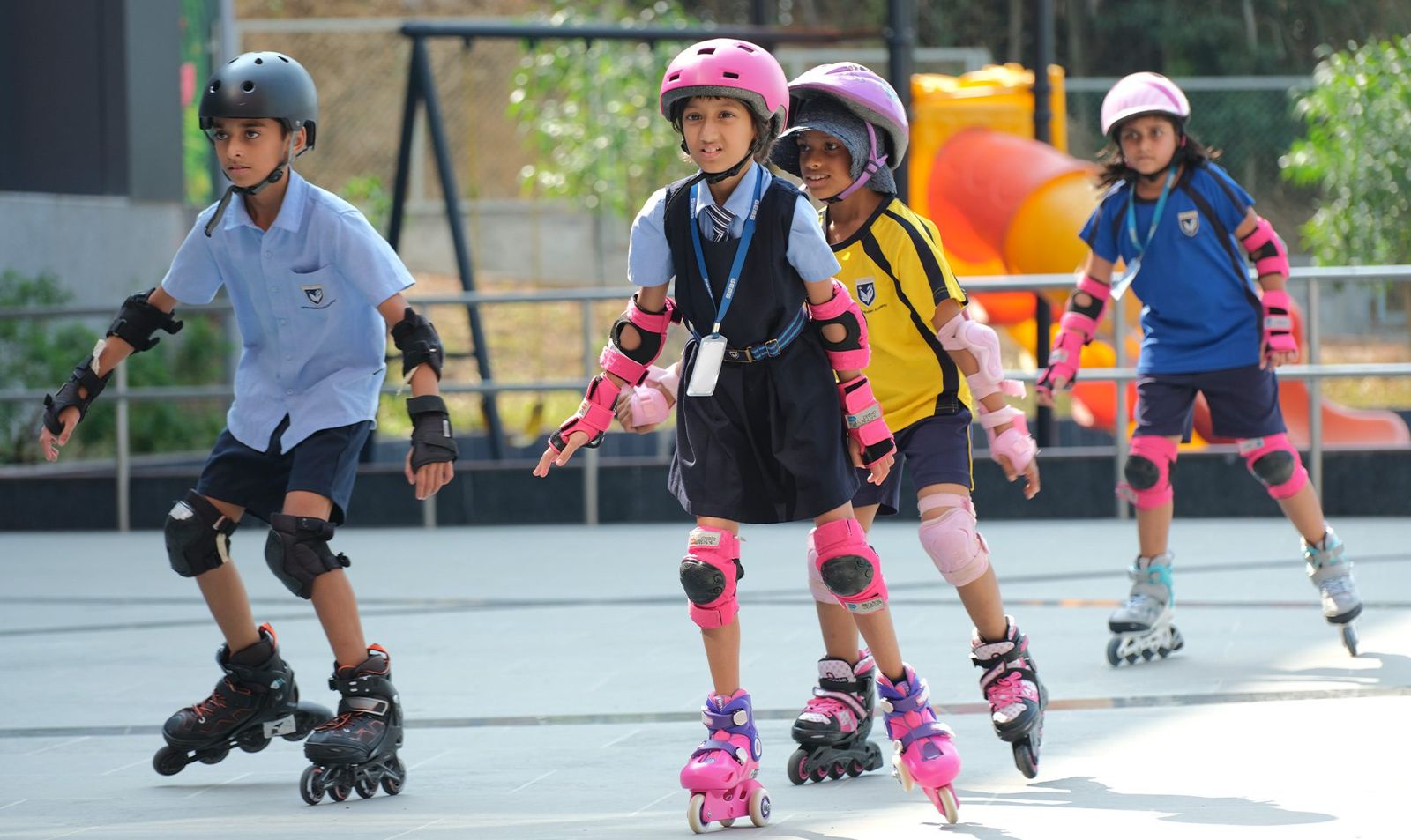 A line of children inline skating in helmets and pads.