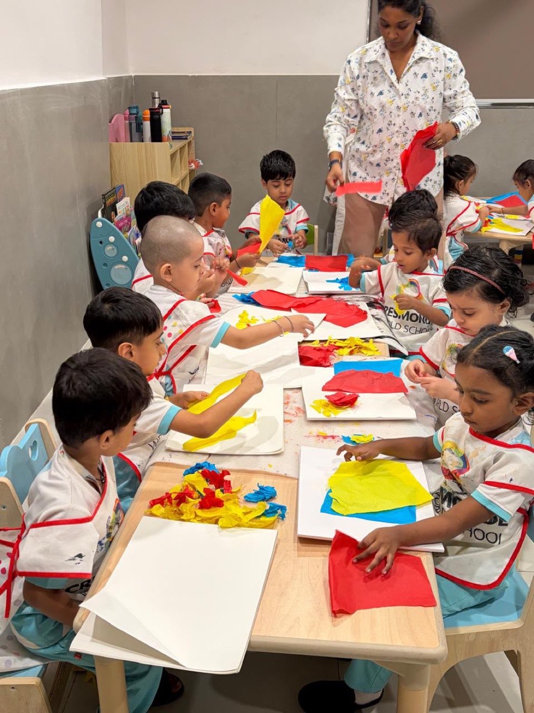 Kindergarten children layering torn kite paper onto the pages of their art journals