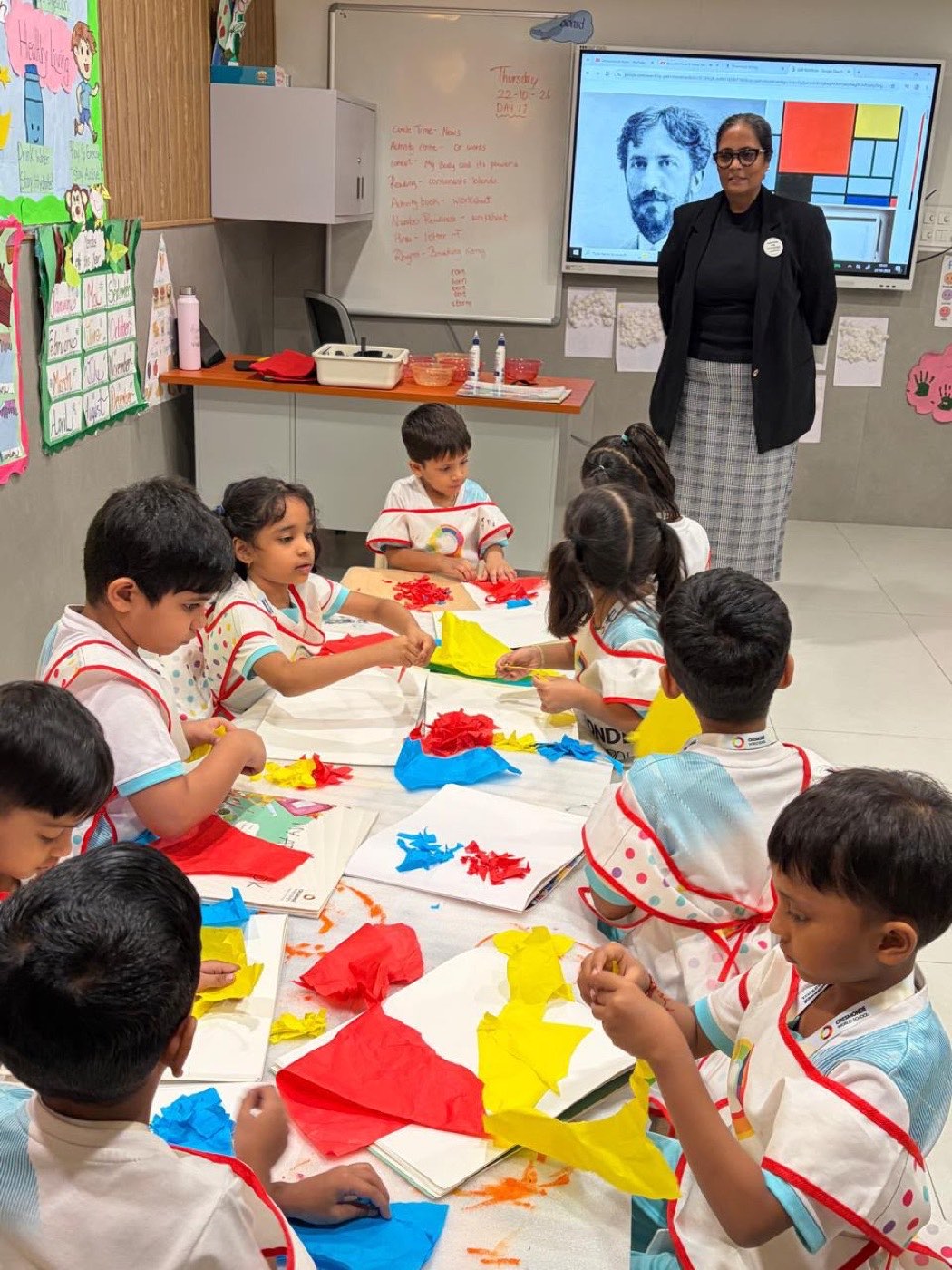 A kindergarten class at work, with Mondrian's painting and portrait shown on the classroom screen