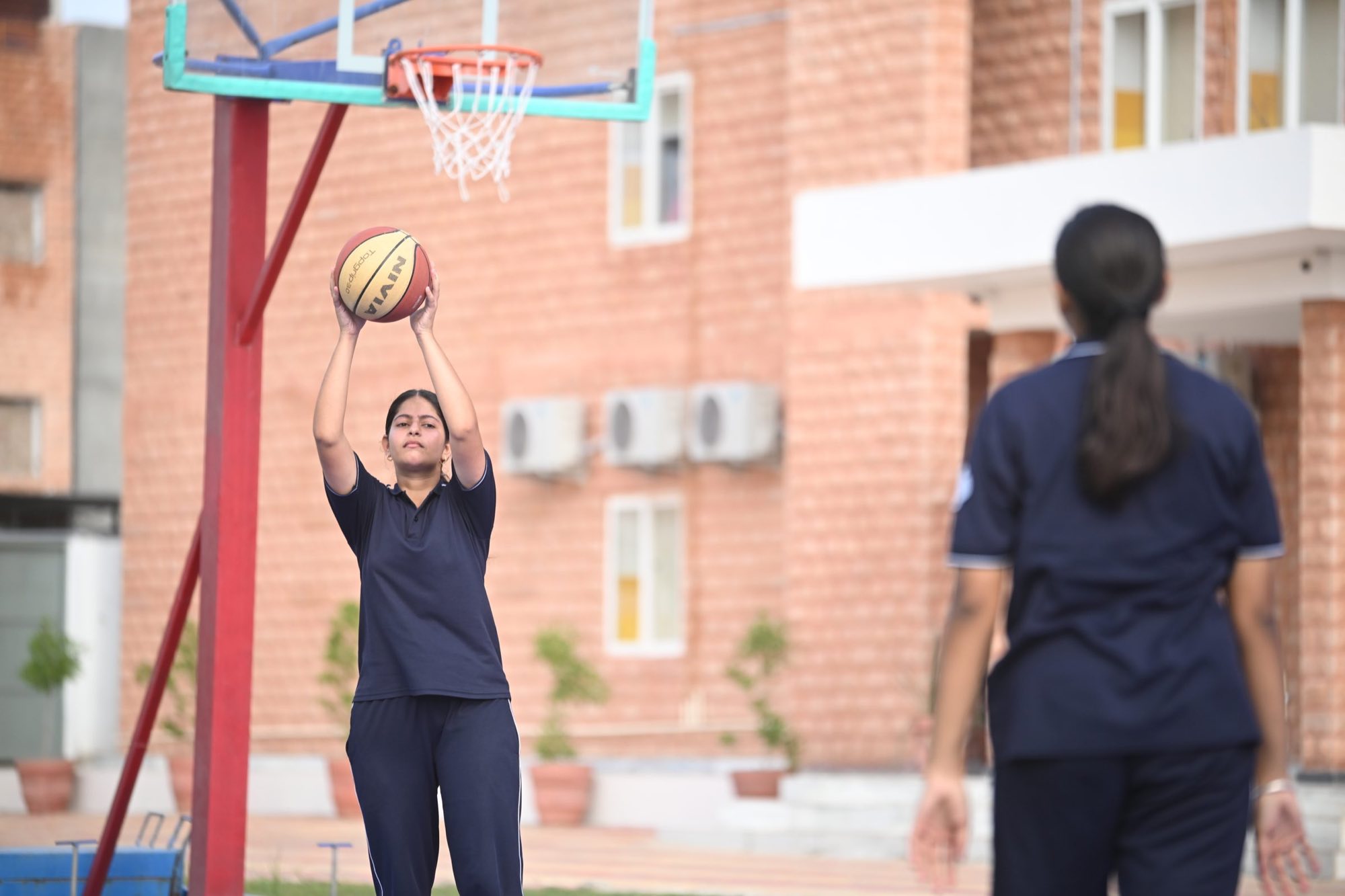 A student shooting a basketball on the outdoor court