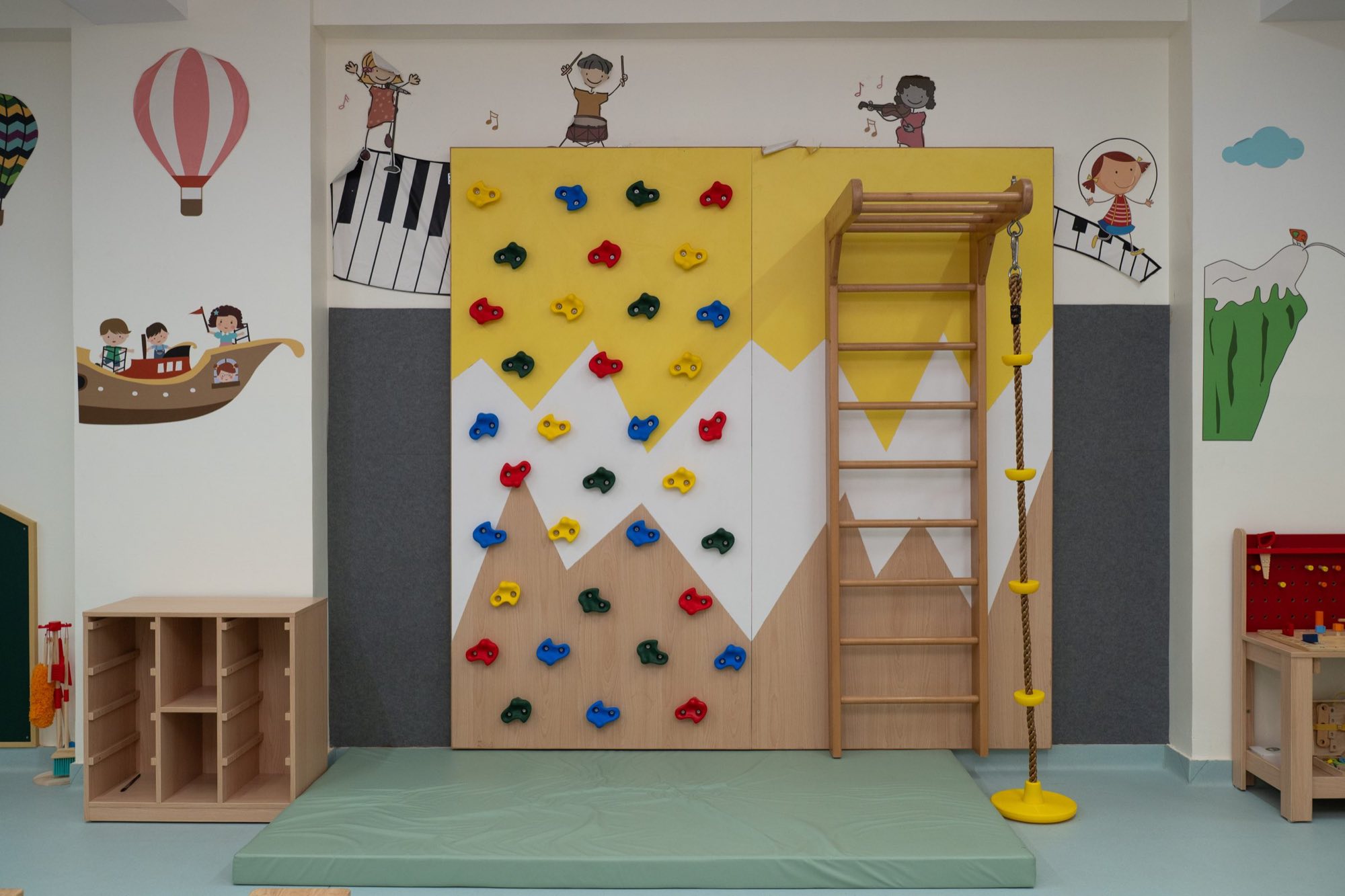 An indoor climbing wall and rope ladder in the early years play area