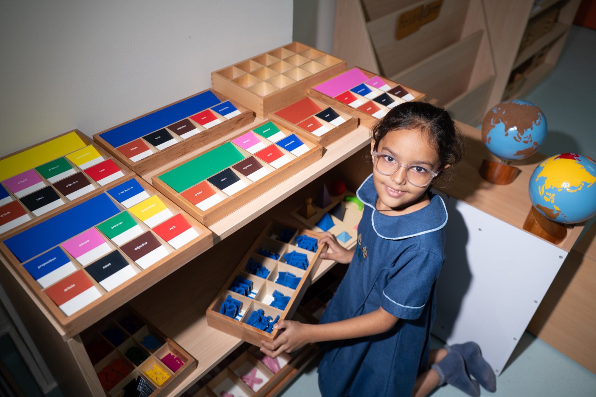 A student choosing Montessori sensorial materials from a shelf